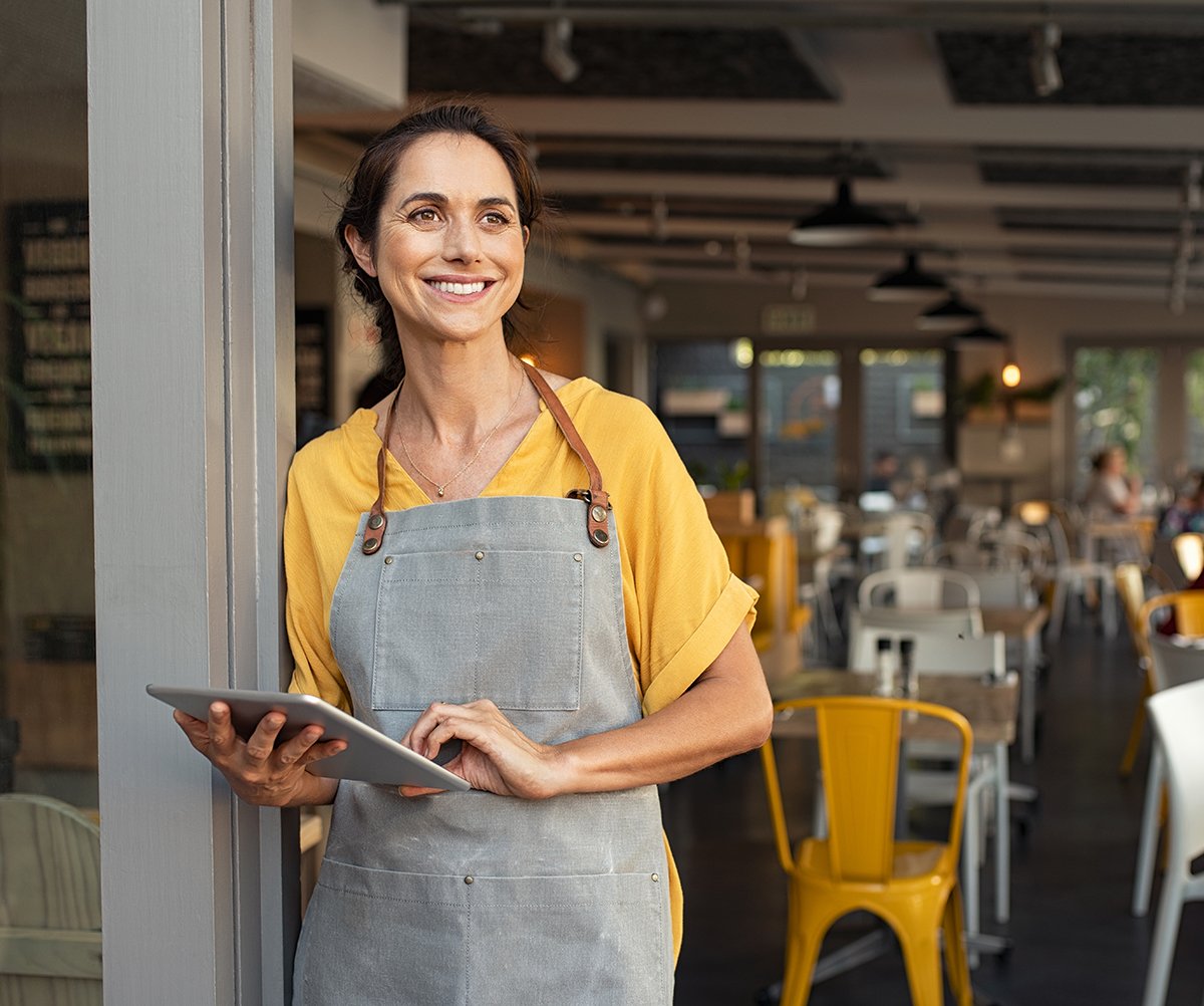 Successful owner standing at cafe entrance